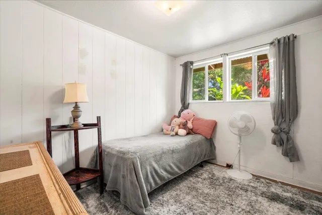 a bedroom with a bed table and a flat screen tv