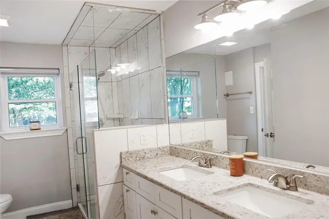 a bathroom with a granite countertop sink a mirror and a shower