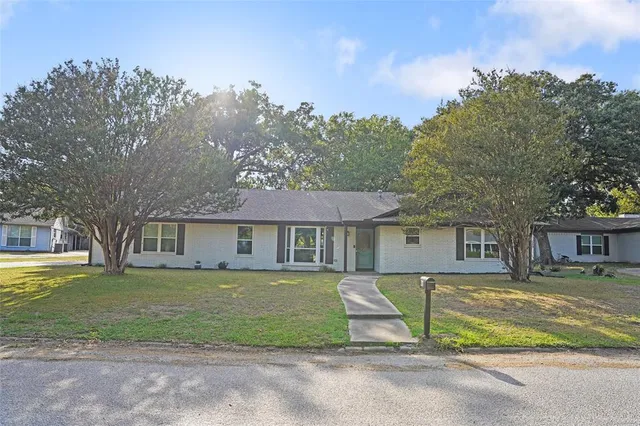 a view of a house with a big yard and large trees