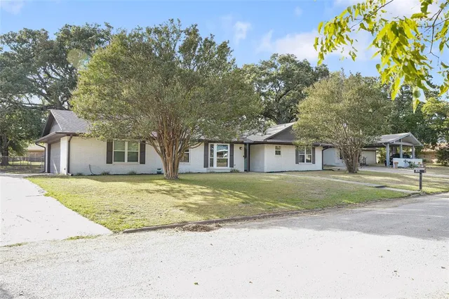 a view of a house with a yard and large trees