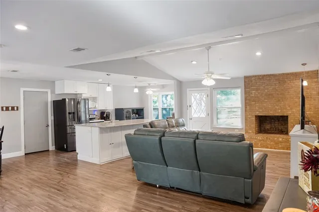 a living room with furniture a fireplace and a open kitchen view