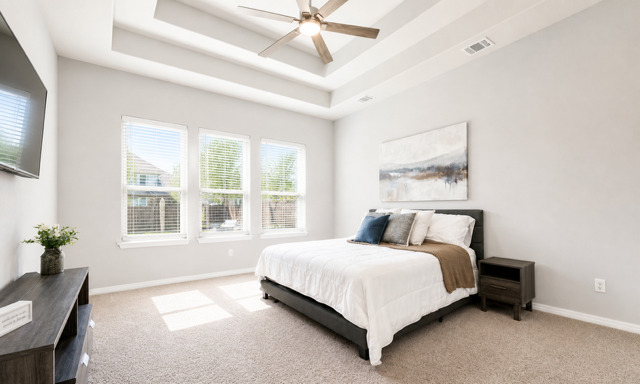 1928 Lakeside Ranch Road Georgetown, TX 78633 - Photo 14 of 37 A tranquil primary bedroom with a spacious bed, a multi-tiered ceiling, and large windows bringing in abundant light.