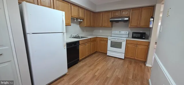 a kitchen with a refrigerator a stove top oven and wooden floor