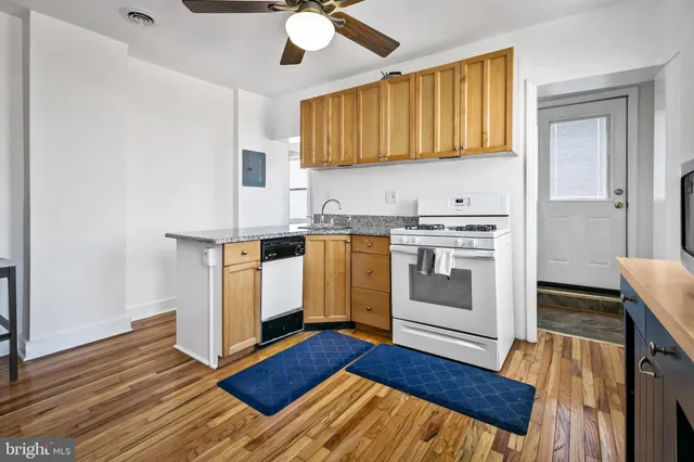 a kitchen with stainless steel appliances granite countertop a stove a sink and a refrigerator with wooden floors