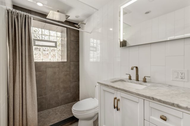 3604 West George Street, Unit G Chicago, IL 60618 - Photo 8 of 19 a bathroom with a granite countertop sink a toilet a mirror and shower