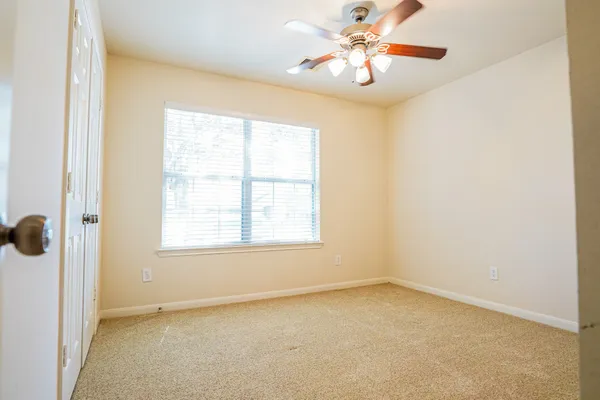 an empty room with a window and a fan