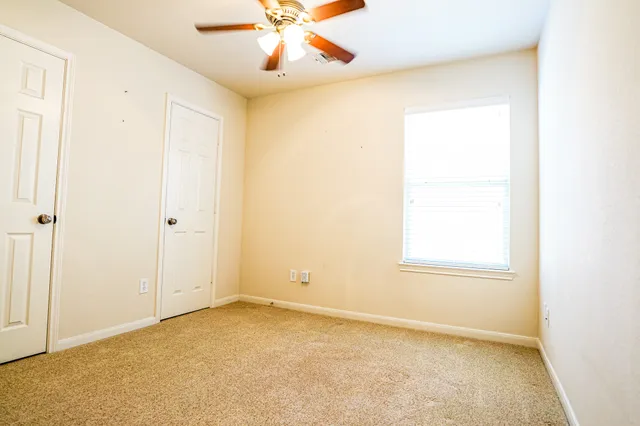 an empty room with windows and fan