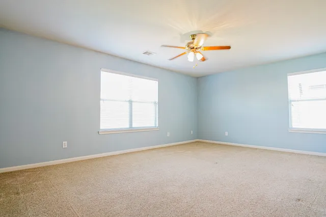 an empty room with windows and chandelier fan
