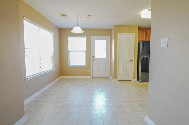 an empty room with windows and chandelier fan