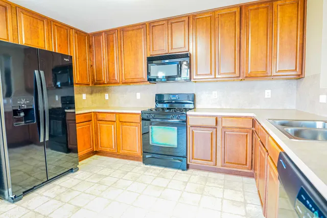 a kitchen with stainless steel appliances granite countertop a stove a sink dishwasher and a refrigerator with cabinets