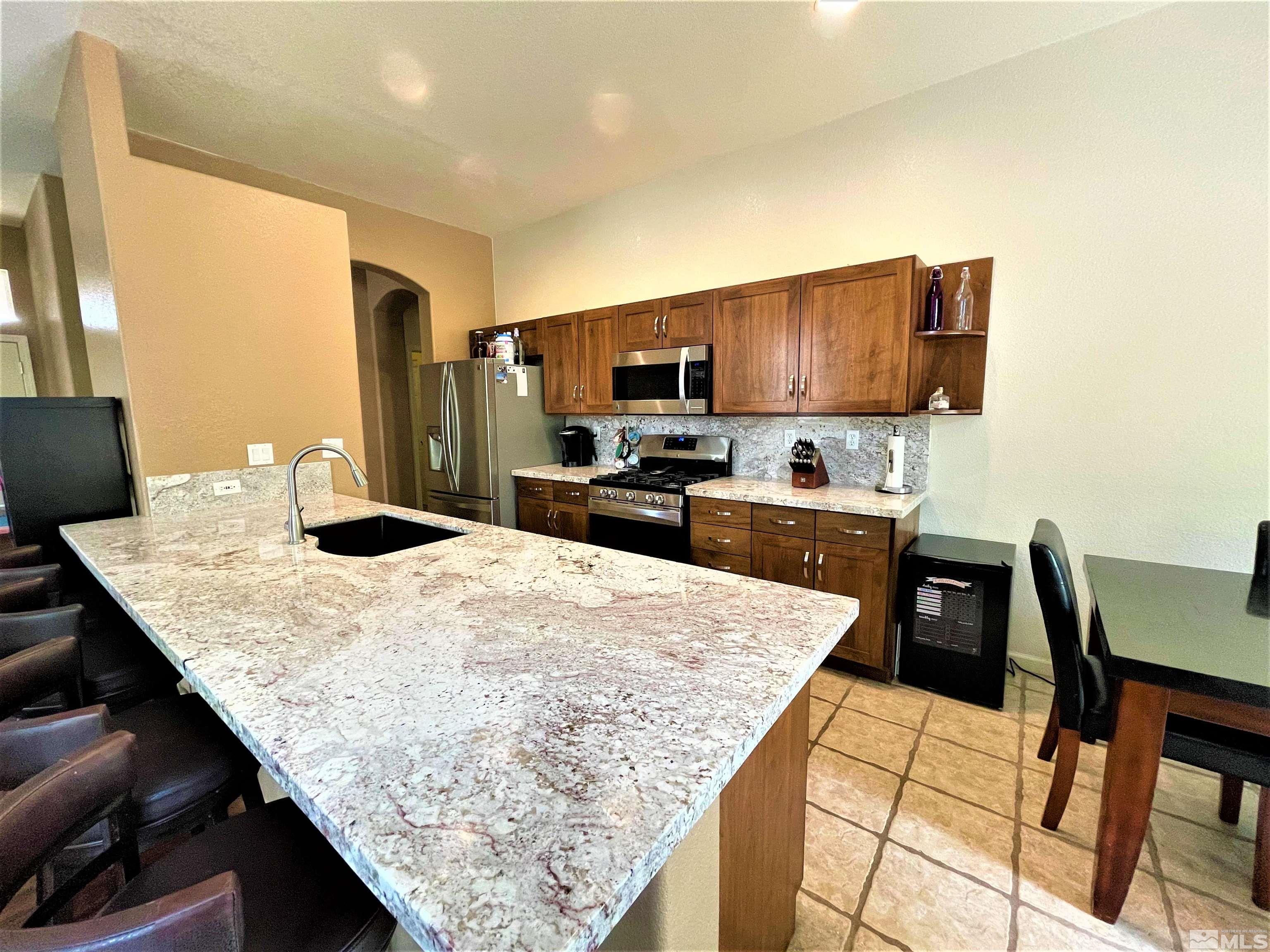 1710 Canyonlands Way Reno, NV 89521 - Photo 3 of 28 a kitchen with a table chairs and a refrigerator