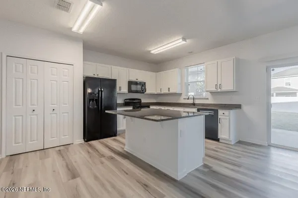 a kitchen with granite countertop a refrigerator stove top oven and sink