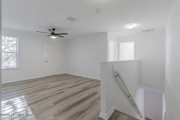 an empty room with windows and fan