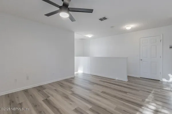 an empty room with wooden floor and windows