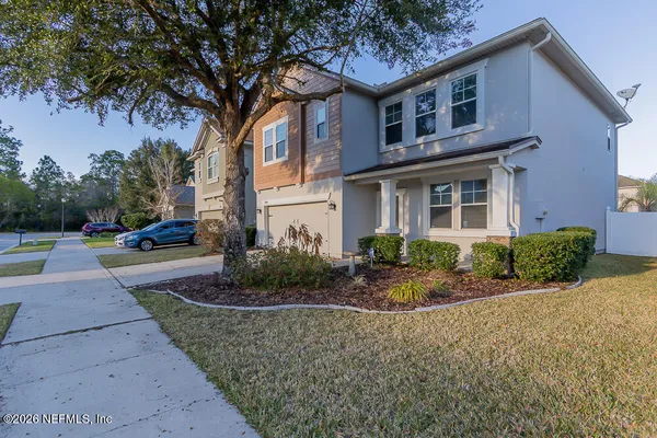 a front view of a house with garden and trees