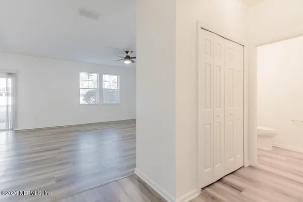 a view of an empty room with wooden floor and a window
