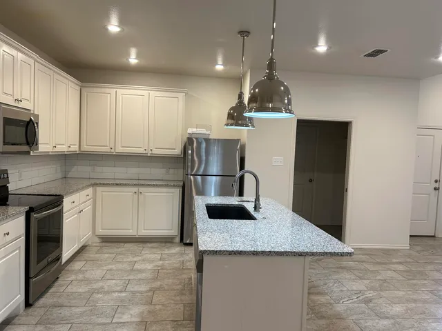 a kitchen with stainless steel appliances granite countertop a sink and a refrigerator