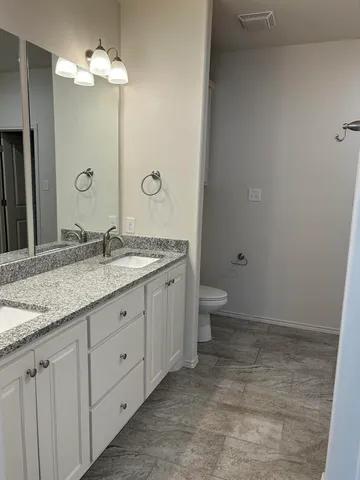 a bathroom with a granite countertop sink a toilet and a mirror