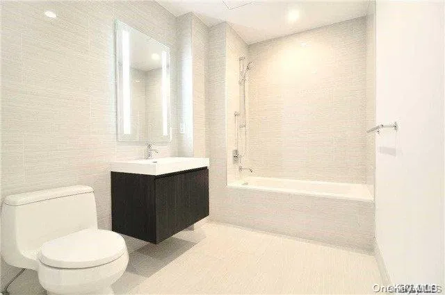 a bathroom with a bathtub shower sink vanity and a toilet