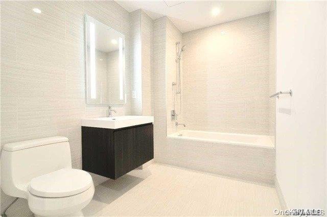 131-05 40 Road, Unit 11T Queens, NY 11354 - Photo 5 of 13 a bathroom with a bathtub shower sink vanity and a toilet