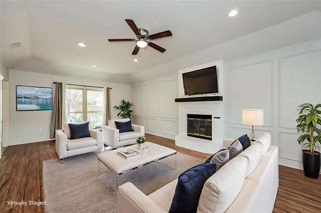 a view of a livingroom with wooden floor a ceiling fan and a window