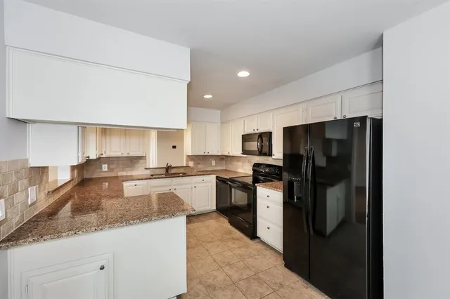 a kitchen with granite countertop white cabinets and sink