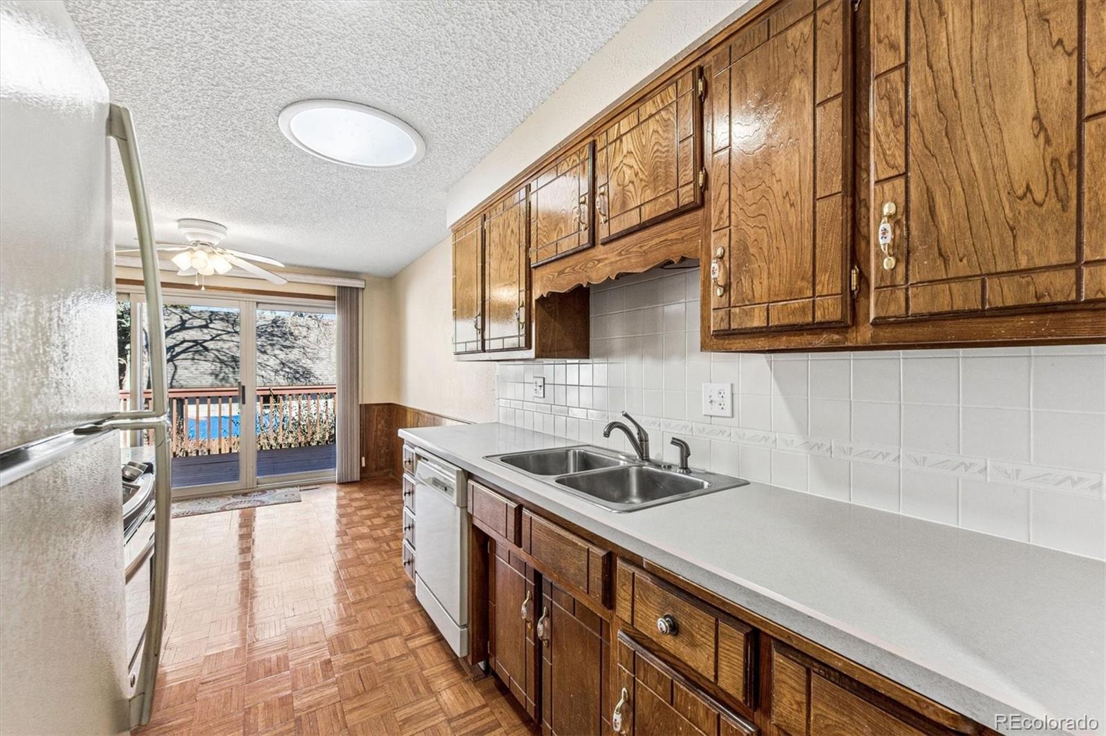 6505 West 34th Avenue Wheat Ridge, CO 80033 - Photo 11 of 28 a kitchen with stainless steel appliances a sink a stove cabinets and a wooden floor