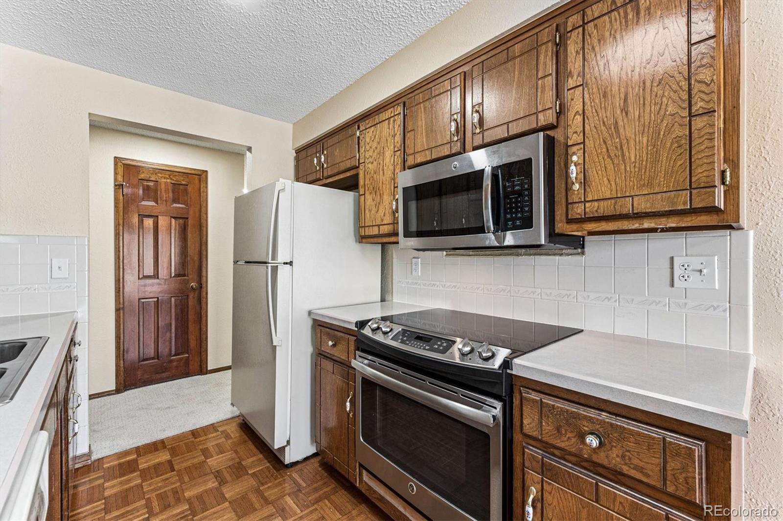 6505 West 34th Avenue Wheat Ridge, CO 80033 - Photo 10 of 28 a kitchen with stainless steel appliances granite countertop a stove microwave and refrigerator