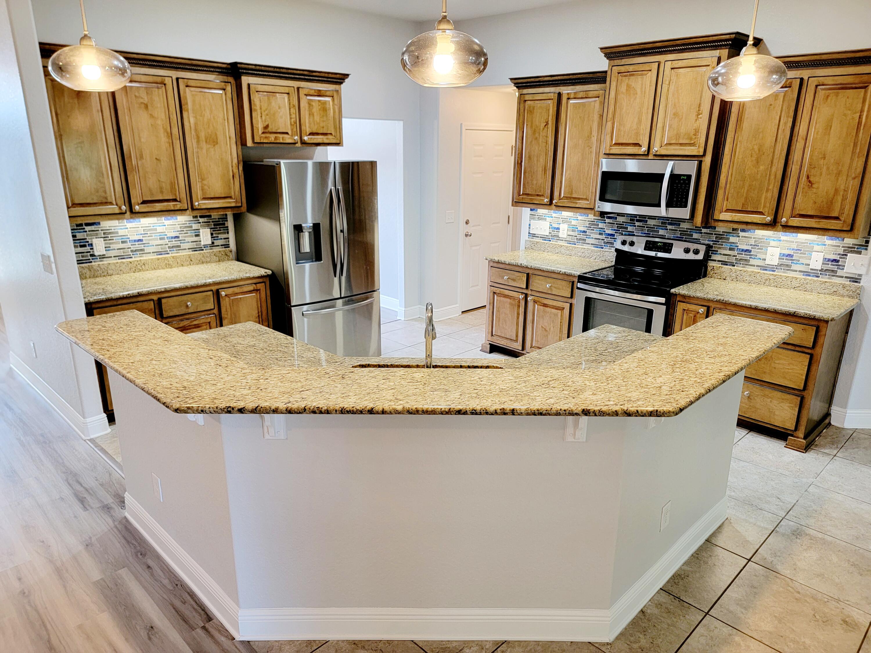 505 Vale Loop Crestview, FL 32536 - Photo 6 of 14 a kitchen with granite countertop a sink a stove top oven a refrigerator cabinets and wooden floor