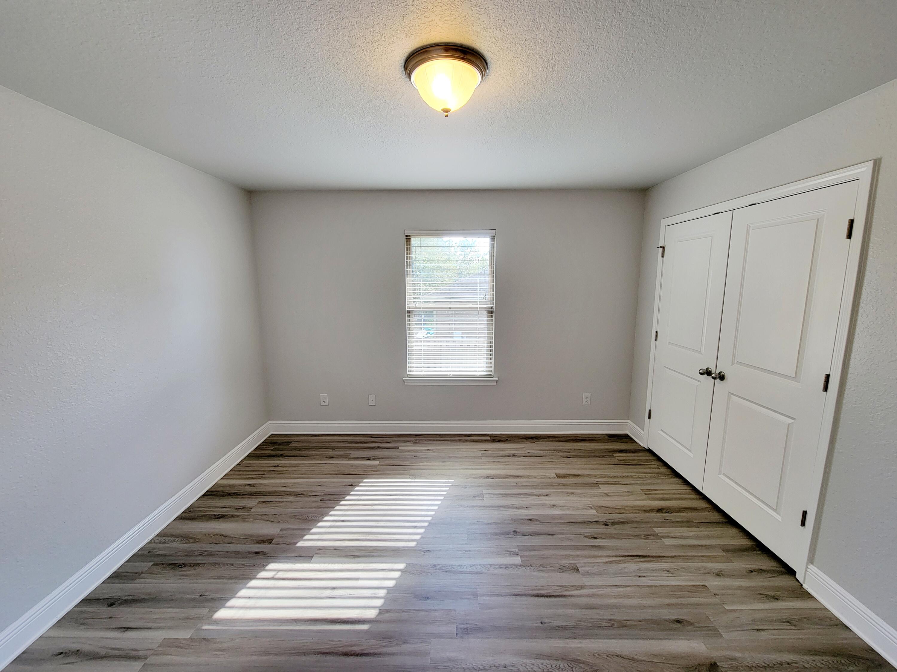 505 Vale Loop Crestview, FL 32536 - Photo 8 of 14 a view of an empty room with wooden floor and a window