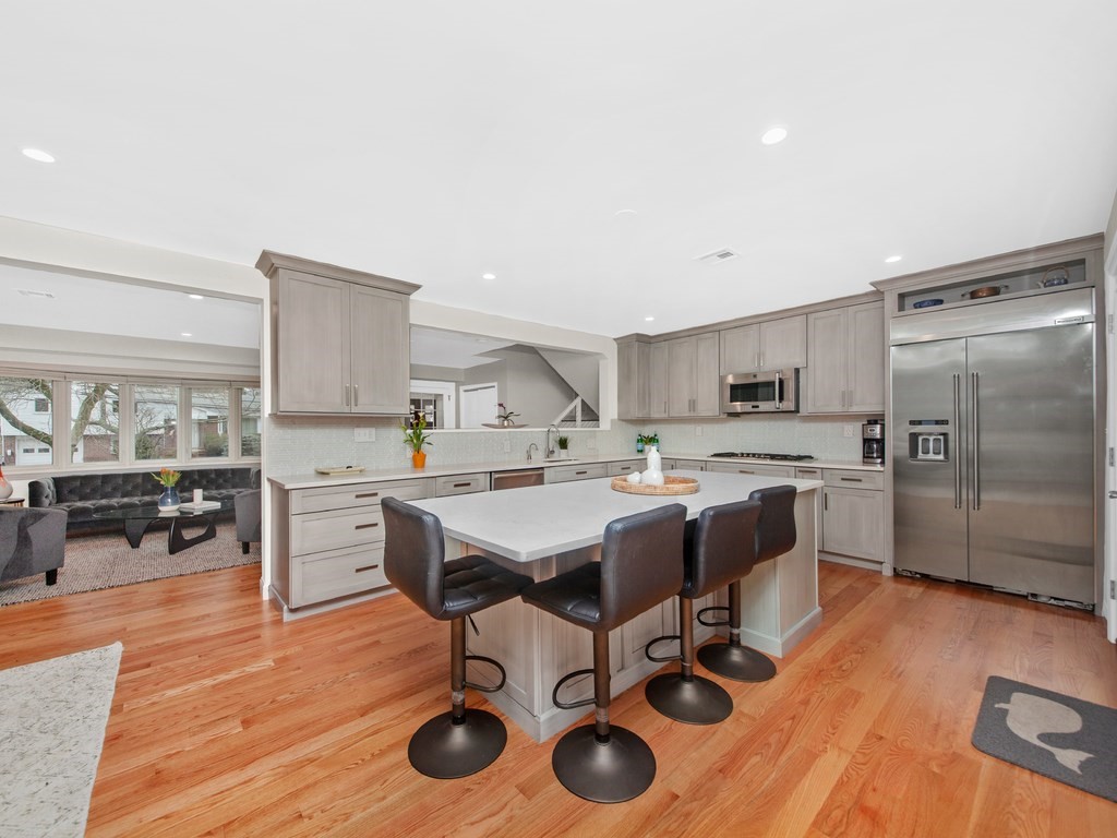 128 Olde Field Road Newton, MA 02459 - Photo 12 of 36 a kitchen with stainless steel appliances kitchen island hardwood floor sink stove dining table and chairs