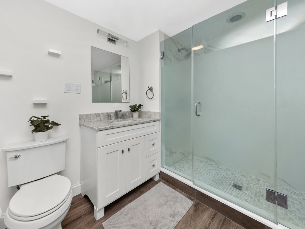 128 Olde Field Road Newton, MA 02459 - Photo 23 of 36 a bathroom with a granite countertop sink toilet a mirror a vanity and shower