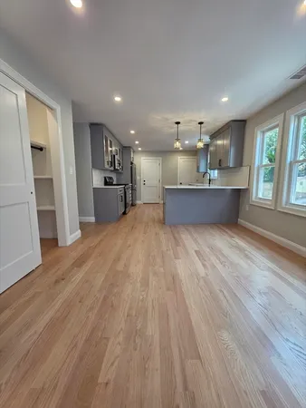 a large space with kitchen island wooden floors and stainless steel appliances