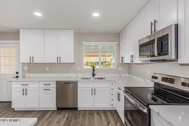 a kitchen with granite countertop a sink a stove and cabinets