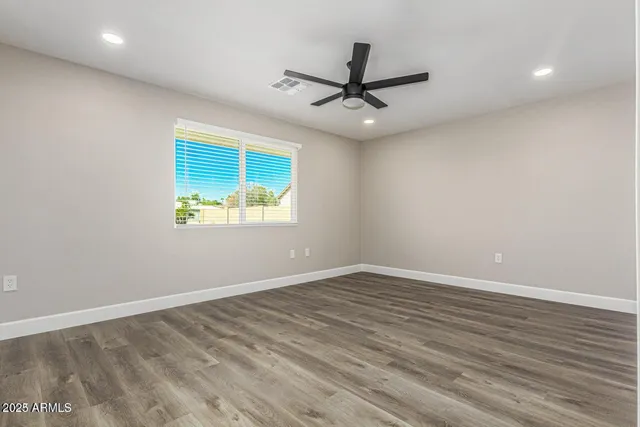an empty room with wooden floor fan and windows