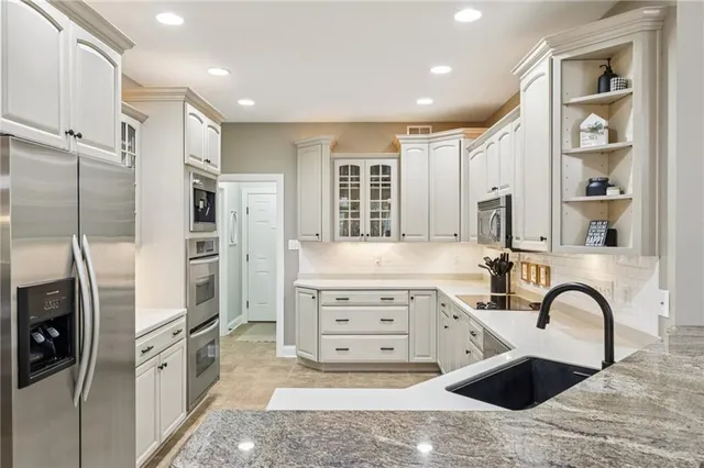 a kitchen with stainless steel appliances kitchen island granite countertop a refrigerator and a sink