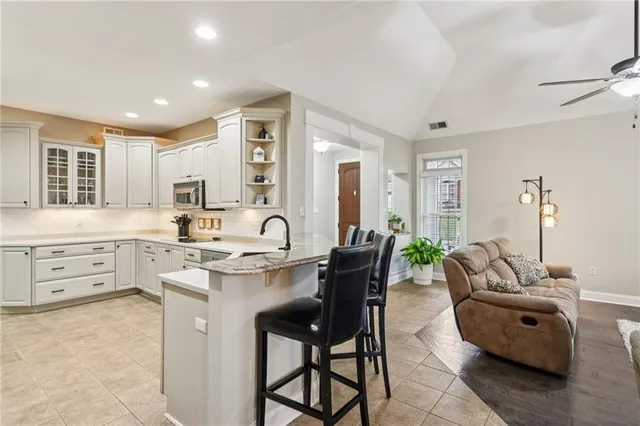a large white kitchen with kitchen island a stove a sink a dining table and chairs