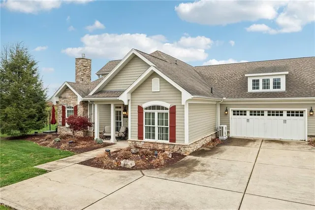 a view of a house with a small yard and large tree