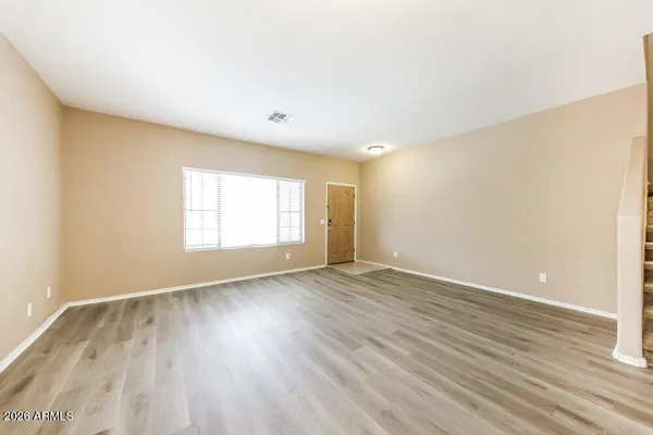 an empty room with wooden floor and windows