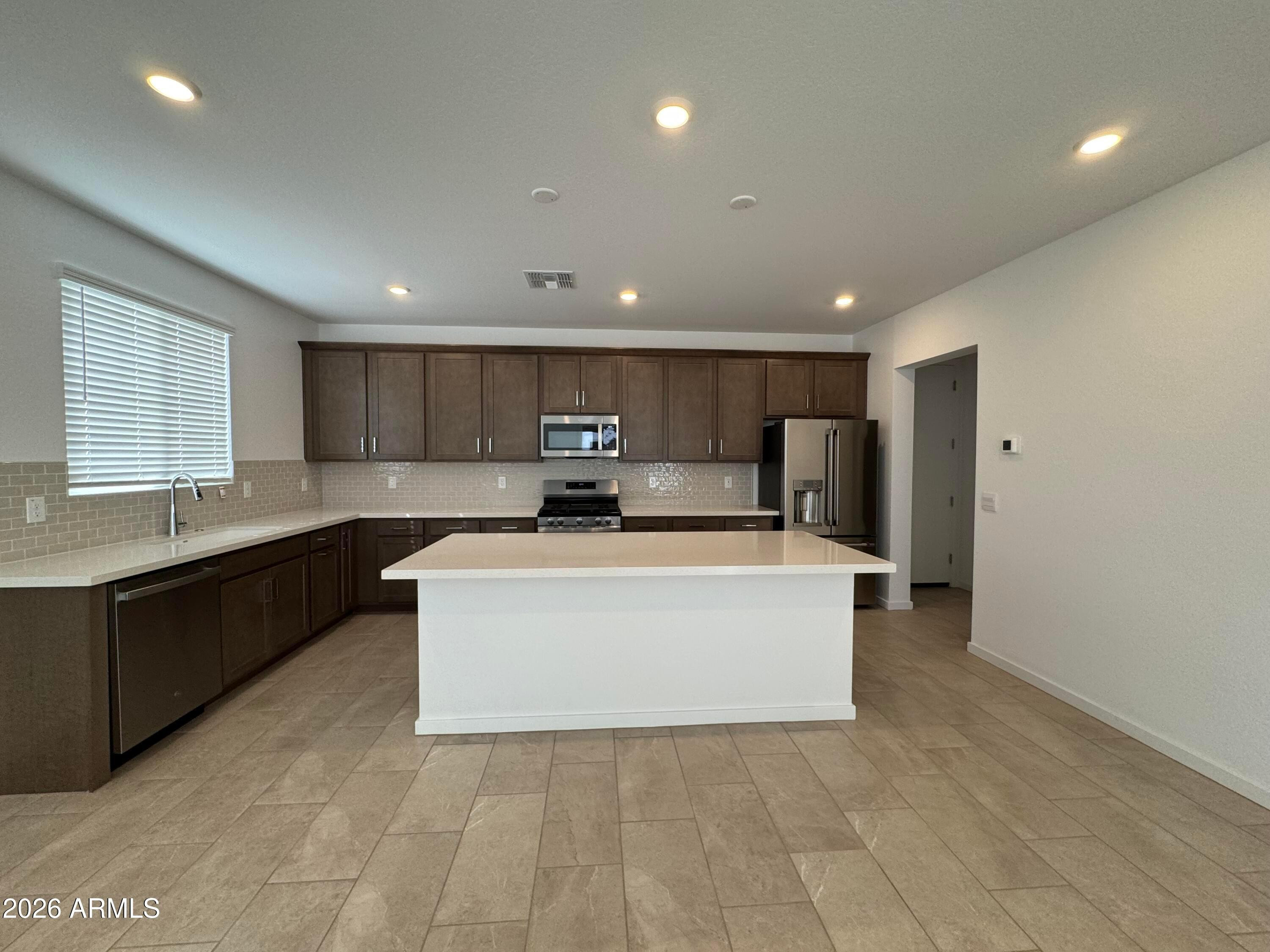 2438 West Rowel Road Phoenix, AZ 85085 - Photo 4 of 30 a large white kitchen with kitchen island a stove a sink a refrigerator and cabinets