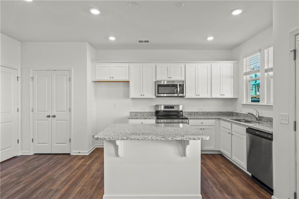 155 Star Court Pendergrass, GA 30567 - Photo 11 of 34 a kitchen with kitchen island granite countertop a sink cabinets stainless steel appliances and a window