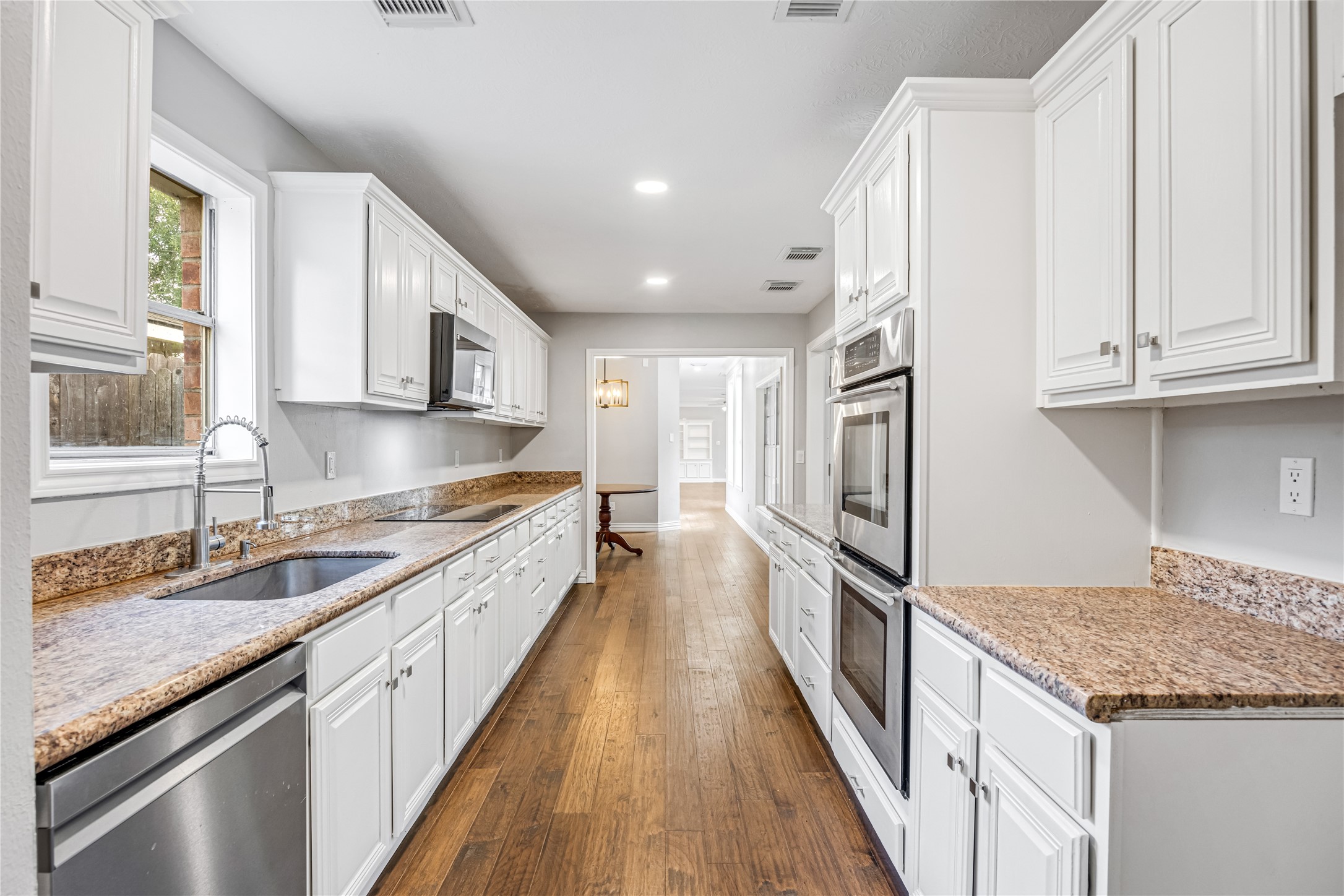 9806 Tanager Lane Conroe, TX 77385 - Photo 12 of 28 a large kitchen with granite countertop a sink and dishwasher a stove top oven with wooden floor