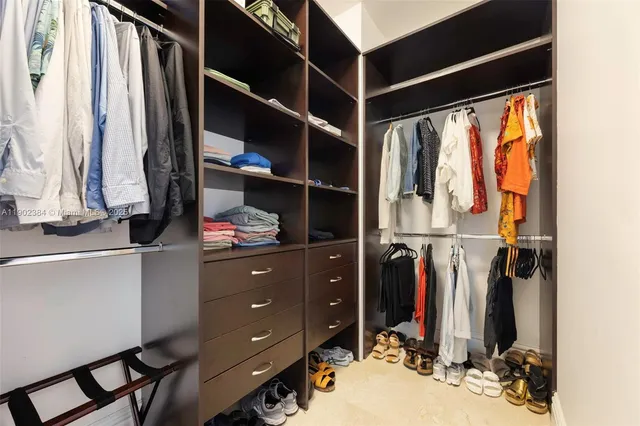 a view of walk in closet with clothes and shoes