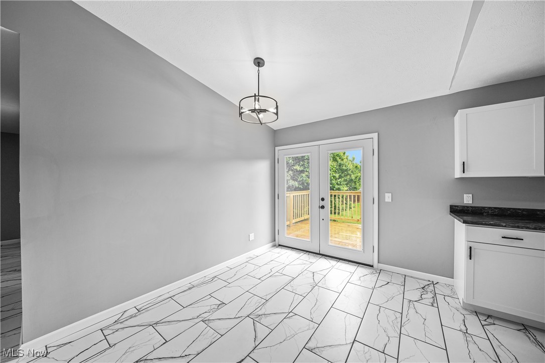 23595 Sandy Creek Road Minerva, OH 44657 - Photo 5 of 32 Unfurnished dining area featuring light marble finish flooring, french doors, a chandelier, baseboards, and lofted ceiling