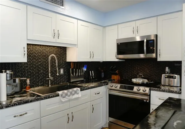 a kitchen with granite countertop a stove and a microwave