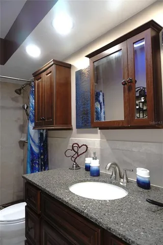 a bathroom with a granite countertop sink a mirror and shower