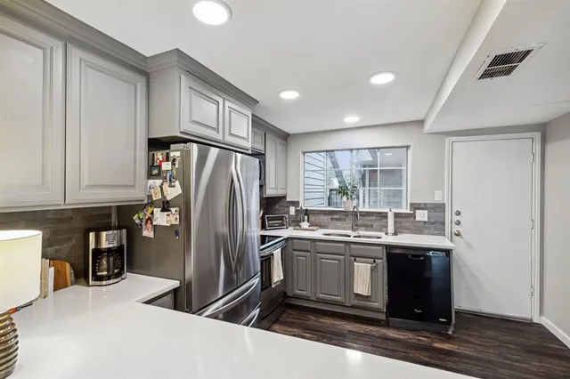 a kitchen with stainless steel appliances granite countertop a refrigerator a sink a stove and white cabinets