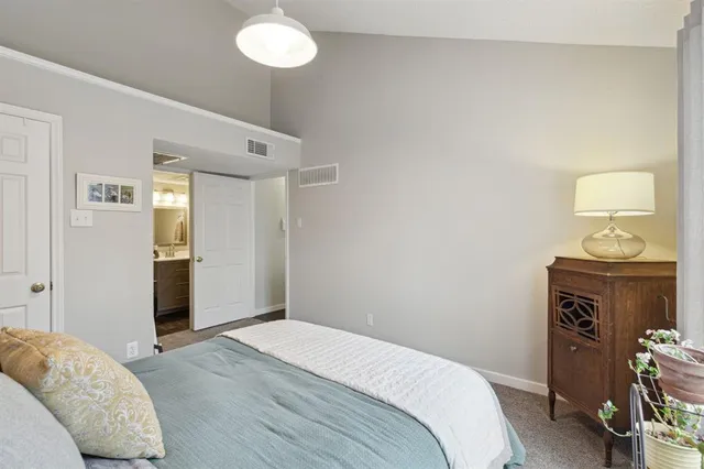 a bedroom with a bed and a lamp on the dresser