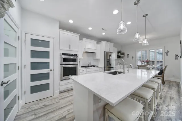 a large kitchen with kitchen island a large island a stove a cabinets and wooden floor