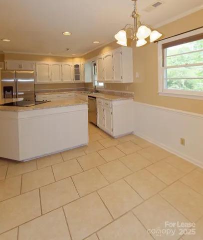 a large kitchen with granite countertop a stove a sink and a white cabinets